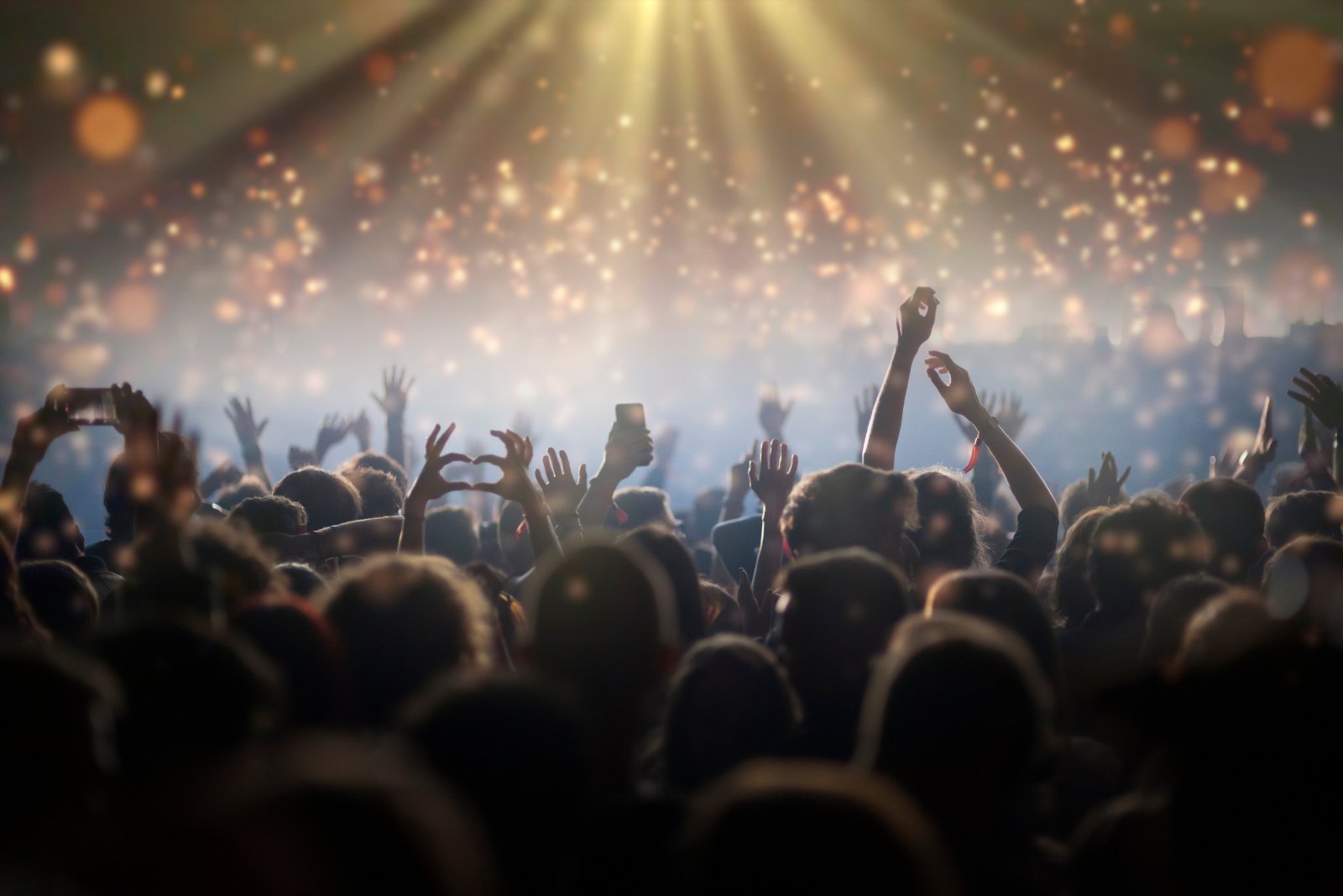 Crowd with raised hands in front of stage lights at a live music show